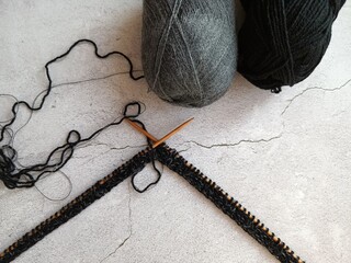 The process of knitting a jumper made of black and gray wool with sequins. High quality photo