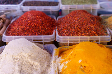 A variety of spices are displayed in different colored containers