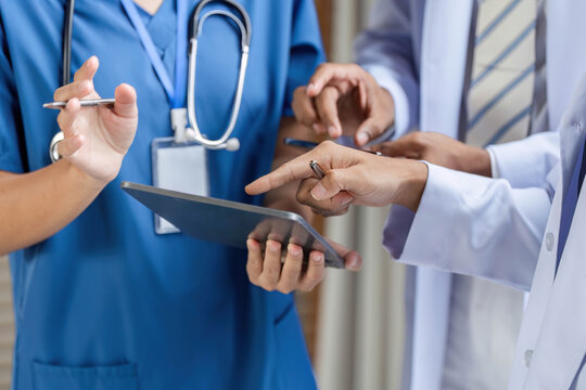 Doctor collaborating with team using tablet in medical consultation - Powered by Adobe