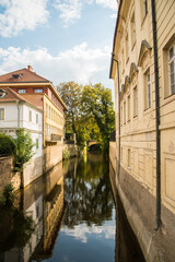 Fototapeta premium Canal between historic buildings with reflections and blue sky