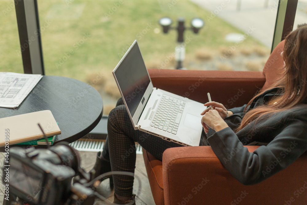 Poster a woman is comfortably sitting in a chair while actively using a laptop computer to perform tasks or