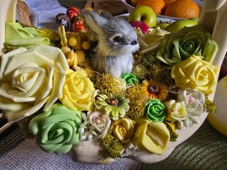 A charming Easter-themed ceramic basket holds a small bunny figurine amidst a colorful arrangement...