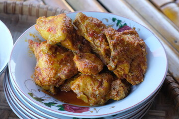 spicy balado chicken on a plate. spicy chicken seasoned with chili, turmeric, ginger, shallots, garlic. balado ayam.
