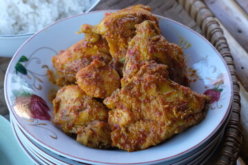 spicy balado chicken on a plate. spicy chicken seasoned with chili, turmeric, ginger, shallots, garlic. balado ayam.