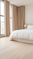 A spacious bedroom with large windows, white bedding, and light wood floors