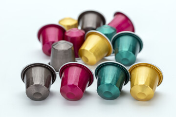 Colorful coffee capsules scattered on white background, featuring various vibrant hues like pink,...