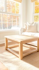 Sunlit room features a light wood coffee table on a neutral rug, near a white couch with pillows, large windows show autumn leaves