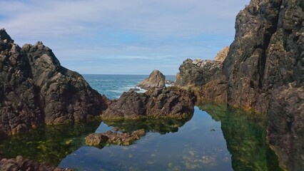 Stunning coastal landscape along California's Highway 1, featuring rugged rocky formations, crystal-clear tide pools, and the vast blue ocean. A breathtaking natural scene showcasing the raw beauty 