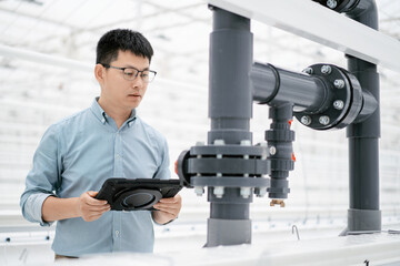 asian male farmer working with digital tablet  in greenhouse