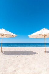 Two white beach umbrellas stand on a pristine, sandy beach facing a calm, blue ocean under a vibrant blue sky