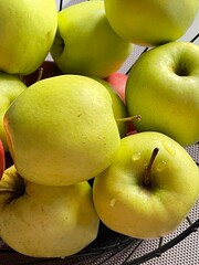 Green and yellow apples with the drops of water in a vase 