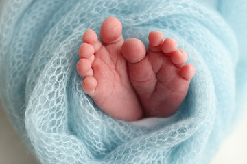 Baby foot on blue soft coverlet, blanket. Close-up of tiny, cute, bare toes, heels and feet of a newborn girl, boy. 