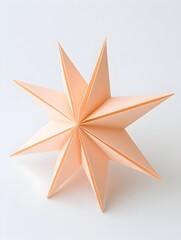Obraz premium A peach-colored, eight-pointed star made of folded paper, sits on a white background