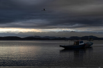 Naklejka premium Boat at Sunset in a Cloudy Day 