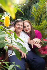 Obraz premium Portrait of an adult daughter hugging her elderly mother in a garden in Yaguara, Huila, Colombia. Concept of family and colombian people