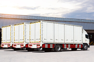 White Trucks on The Parking Lot at The Warehouse. Shipping Cargo Container. Trucks Loading Goods at...