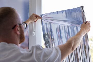 Man tinting windows at home with sun protection film.