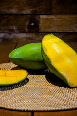 Fresh ripe mango sliced in half, revealing juicy golden flesh. Perfect for tropical fruit, healthy food, summer, and natural snack themes. On dark wooden background.