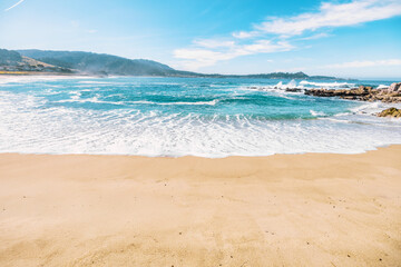 Scenic view of Carmel State Beach in California with golden sand, turquoise waves, and rugged coastal cliffs. A peaceful and sunny seaside landscape perfect for travel and nature themes