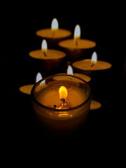 The central candle is sharply focused, surrounded by six warm, glowing candles creating a cozy and calm atmosphere