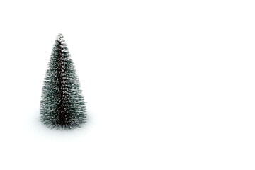 On a white background in the snow stands a small toy fir tree.