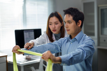 Obraz premium Female doctor assisting male patient stretching with resistance band during physical therapy session in medical office
