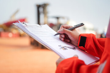 A maintenance engineer is checking on checklist to verify the condition of forklift or heavy...