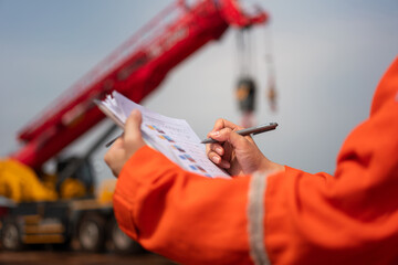 An engineer or foreman is checking on safety checklist form of lifting crane at the drilling rig...