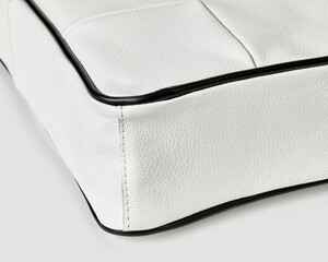 Close-up of white leather bag showing stitching detail and black piping
