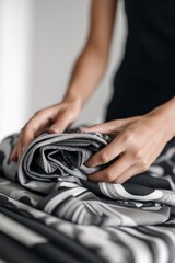 Fototapeta premium Hands Folding Grey and Black Fabric in a Cozy Indoor Setting