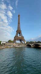 Obraz premium Iconic view of the Eiffel Tower from the Seine River on a sunny day with clear blue skies. A classic Parisian scene capturing architecture, water, and tourism.