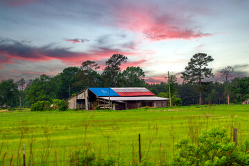 Barn with a Texas flag painted on the tin roof in rural Texas with a dramatic sky