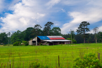 Barn with a Texas flag painted on the tin roof in rural Texas with a dramatic sky
