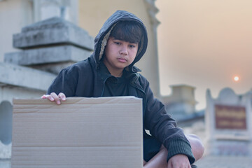 Portrait young asian homeless boy which living and sitting beside rural road, sunlight edited, near...