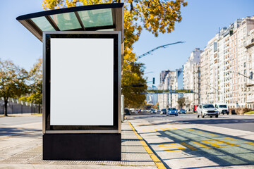 A vertical blank billboard at a bus stop shelter in Buenos Aires, Argentina along Libertador avenue in autumn. Copy space poster into a lightbox to display advertising content