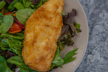 Breaded fish Haddock on a salad ready to eat