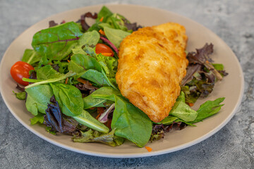 Breaded fish Haddock on a salad ready to eat