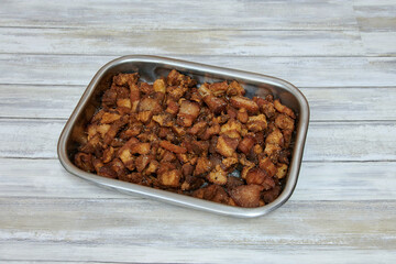 A tray of bacon and bread crumbs. The bacon is cut into small pieces. The tray is silver