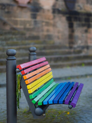 Holzbank vor Gebäude in Regenbogen Farben gestrichen