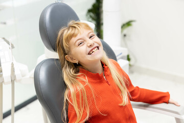 A joyful child sitting in a dental chair, smiling broadly, conveying a sense of comfort and ease during dental visits.