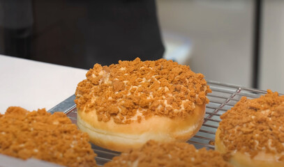 Close-up of a donut topped with golden cookie crumble on a cooling rack, showcasing rich texture...