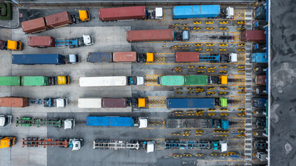 Plakat Aerial view semi trailer trucks stand on the parking lot and wait for loading and unloading cargo container at container terminal port, Global business logistic transportation semi trailer trucks.