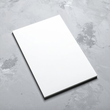 A pristine, blank sheet of white paper lies flat against a textured grey background, creating a minimalist and serene visual contrast.