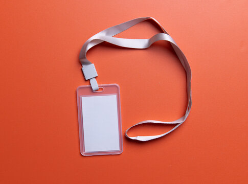 Mockup of a blank white ID card with a white lanyard on orange background