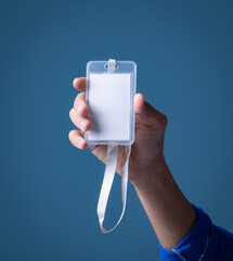 Man's hand holding id badge on blue background