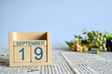 September 19, Calendar cover design with number cube with fruit on newspaper fabric and blue background.	