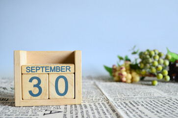 September 30, Calendar cover design with number cube with fruit on newspaper fabric and blue background.	