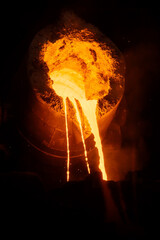 Metal casting process in metallurgical plant, molten metal is pouring from ladle, close up