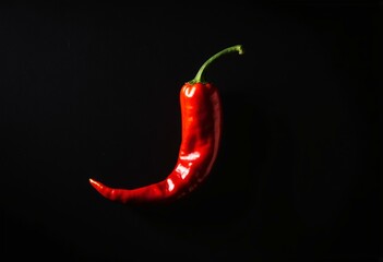 A red hot chili pepper on a black background.