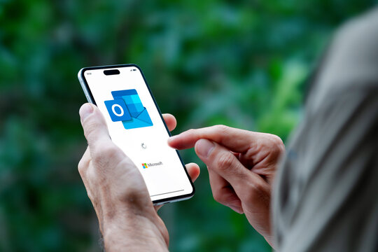 Man holding a mobile phone opening Outlook app for email of Microsoft. ROSARIO, ARGENTINA - APRIL 30, 2025.